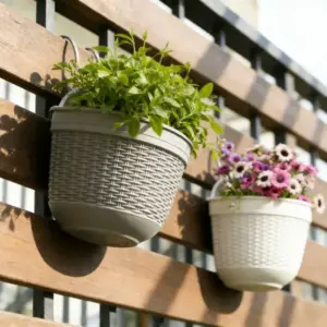 Zwei Hängetöpfe in Grau und Weiß mit Blumen am Zaun