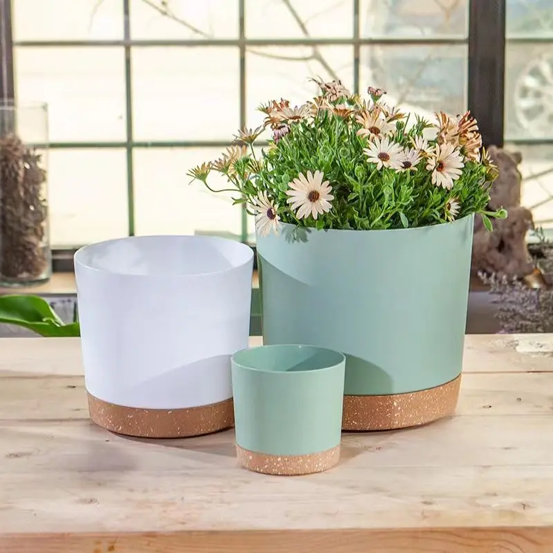 Drei Übertöpfe in Weiß und Mintgrün mit gesprenkeltem Untersetzer, einer davon mit Blumen